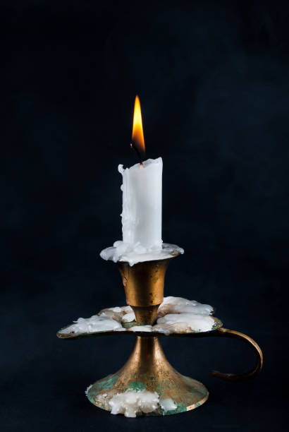 istock White candle burning in old candlestick and smoke in background 853560808