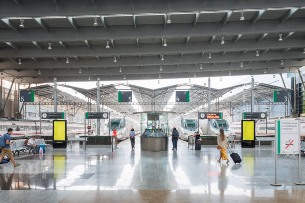 Interior of Mario Zambrano train station in Málaga, Spain. View towards the ticket verification counter, trains and station platforms.