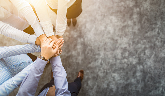 Close up top view of young business people putting their hands together. Stack of hands. Unity and teamwork concept.