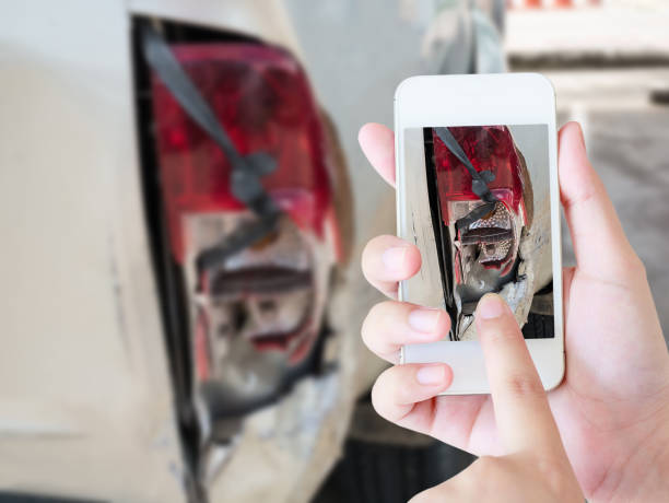 mujer utilizando teléfonos inteligentes para tomar fotos de daños de coche - accidente de automóvil fotos fotografías e imágenes de stock