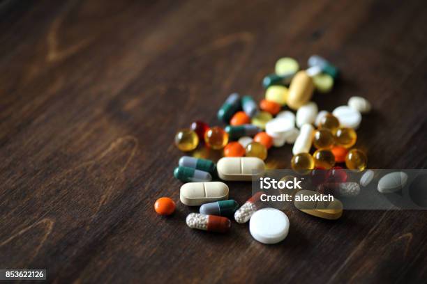 Medications And Tablets On A Wooden Texture Table Stock Photo - Download Image Now - Capsule - Medicine, Pill, Table