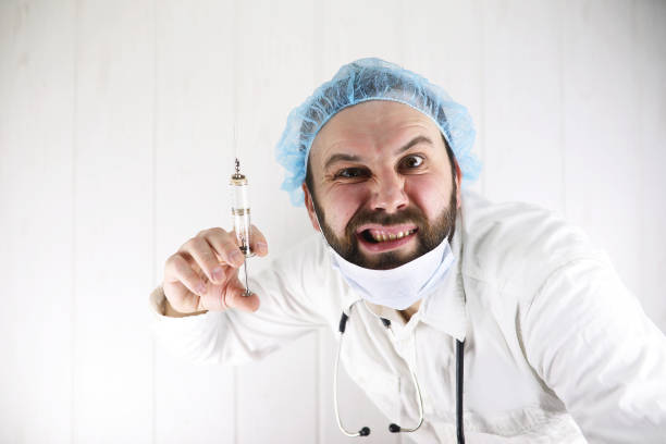 istock Crazy bearded doctor in a white coat and old syringe 853630998