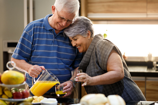 A happy elderly couple having healthy breakfast with orange juice.
