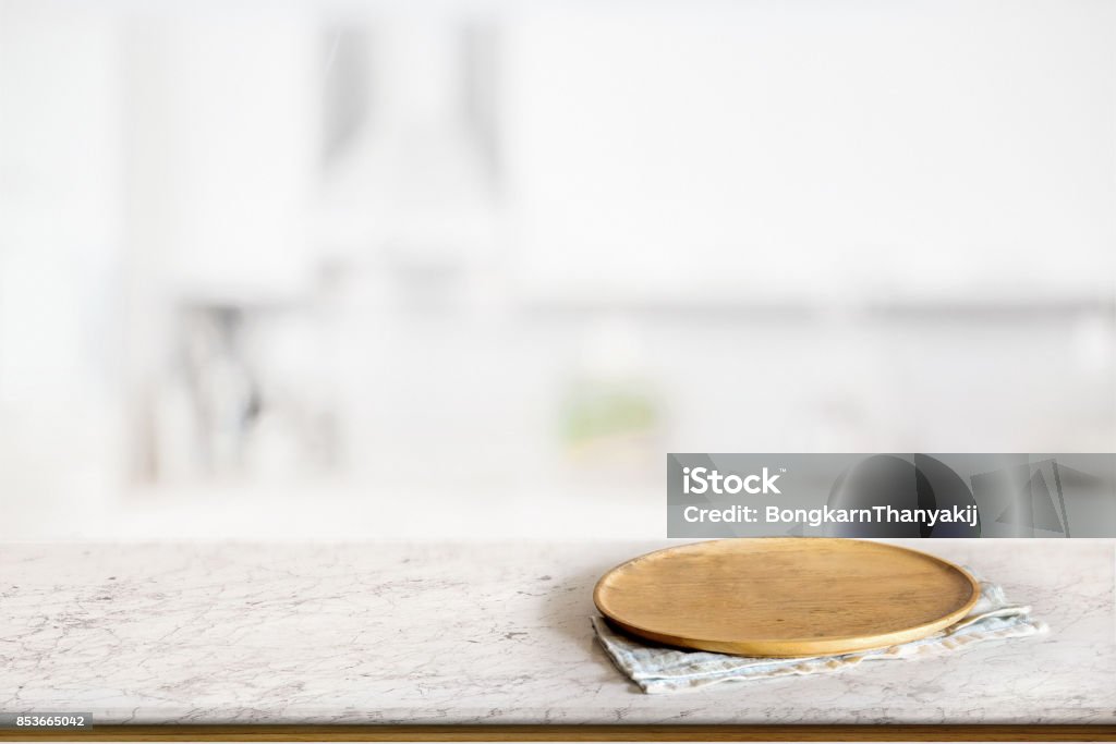 Food montage concept Empty round wooden plate or wooden dish on marble counter in blurred kitchen background. For food and product display montage. Plate Stock Photo