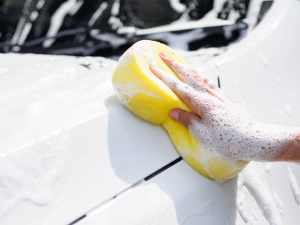 istock Woman hand with yellow sponge washing car 853676178