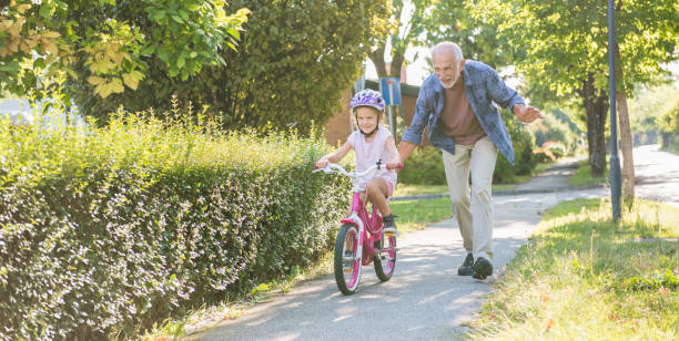 mała dziewczynka nauka jeździć na rowerze z dziadkiem - child spring family little girls zdjęcia i obrazy z banku zdjęć