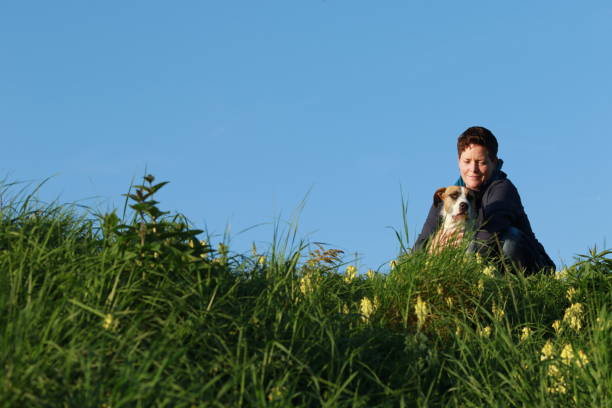 istock Woman sitting in meadow with her dog 853744418