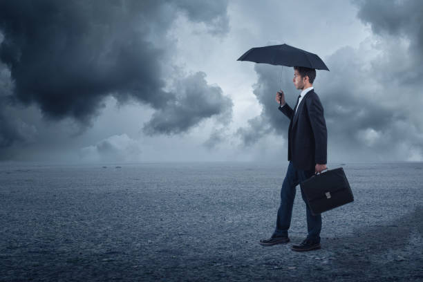 istock Businessman with umbrella standing at cloudy background 853752998