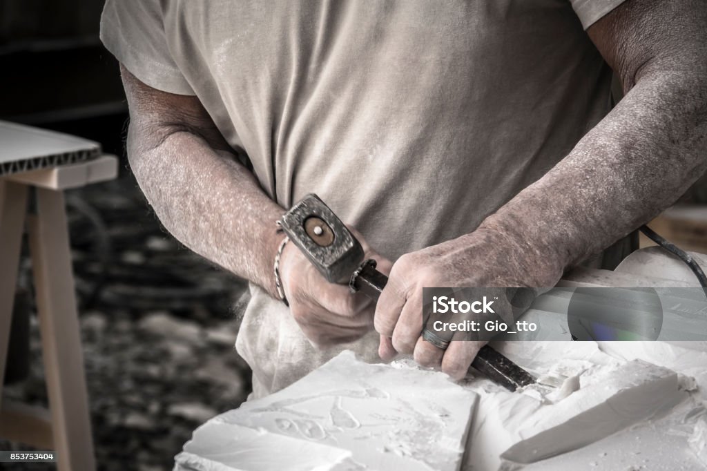 Detail of artist's hands sculpting marble with hammer and chisel Sculptor Stock Photo