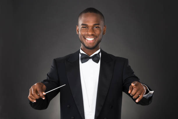 Portrait Of Music Conductor With Baton Portrait Of Happy Music Conductor With Baton Against Black Background conductors baton photos stock pictures, royalty-free photos & images