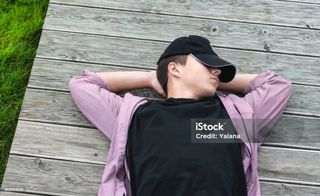 young man has a rest lying on the boards Young man lying down on wooden boards Horizontal Stock Photo