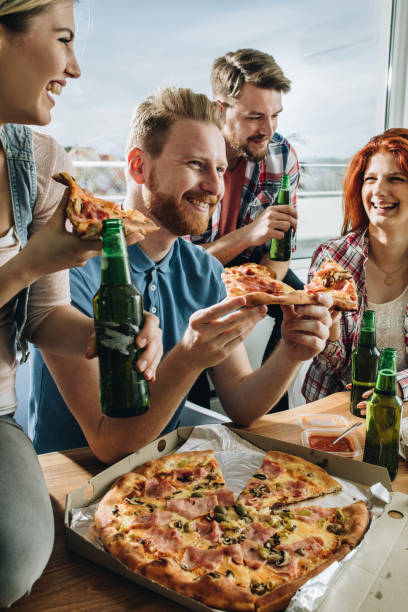 Happy friends having fun while eating pizza and drinking beer.