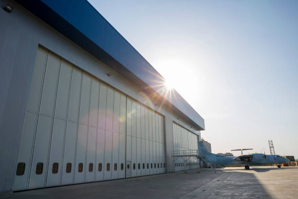 Airport hangar from the outside with big tall doors. Bright blue sky with sunlight.