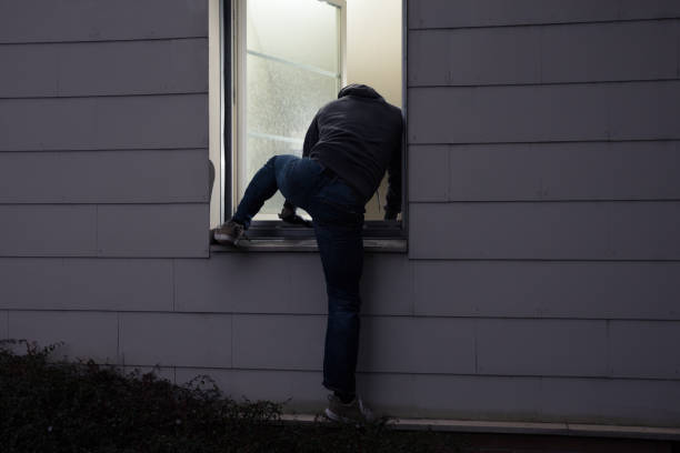 ladro che entra in casa attraverso la finestra - burglary foto e immagini stock