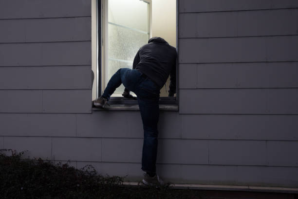 Burglar Entering House Through Window Rear View Of A Burglar Entering In A House Through A Window burglar stock pictures, royalty-free photos & images