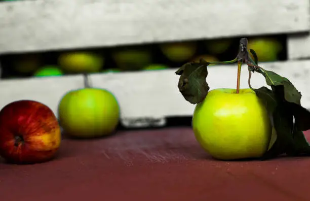 Fresh green apple, against the background of a box. On a red table