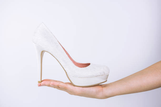 Hand Holding Bridal High Heel Shoe On White Background