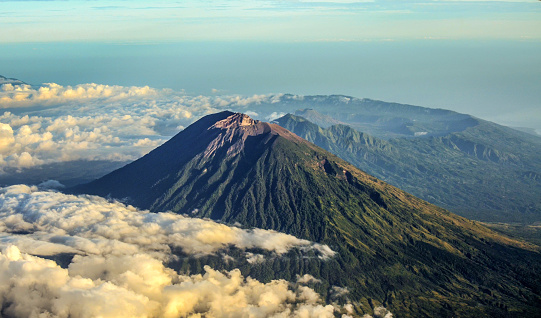 Mount Agung is the highest volcano in Bali and it is an active volcano. The picture was taken from airplane window just a moment after the sunrise. From this point of view, we can see Mount Agung in the foreground with mount Abang and mount Batur in the background.