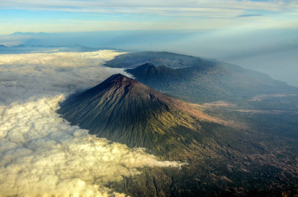 Mount Agung is the highest volcano in Bali and it is an active volcano. The picture was taken from airplane window just a moment after the sunrise. From this point of view, we can see Mount Agung in the foreground with mount Abang and mount Batur in the background.