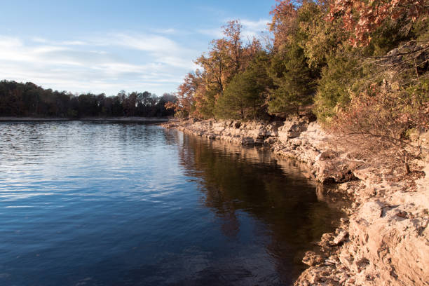 Blue Sky and Blue Water at Fellows Lake, Springfield, Missouri Sunny autumn afternoon at a lake in Springfield, Missouri, USA. Rocky edge to the lake surrounds the calm water. Sky is blue with a few white clouds. springfield missouri photos stock pictures, royalty-free photos & images