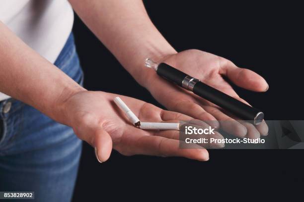 Woman Offers A Choice Between Tobacco Cigarette And Electronic Cigarette Stock Photo - Download Image Now