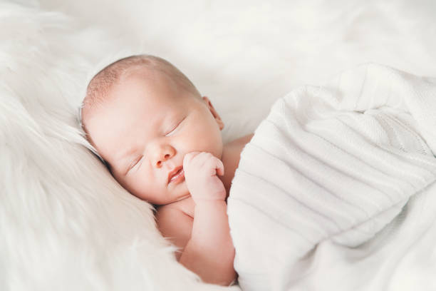 istock Sleeping newborn baby in a wrap on white blanket. 853843544