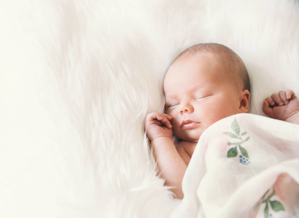 istock Sleeping newborn baby in a wrap on white blanket. 853843582