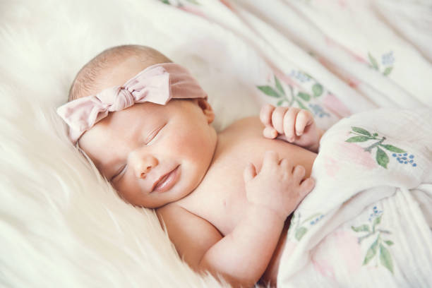 Sleeping newborn baby in a wrap on white blanket.