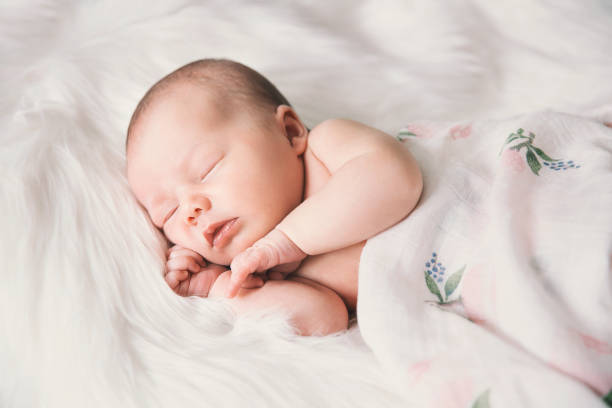istock Sleeping newborn baby in a wrap on white blanket. 853843672