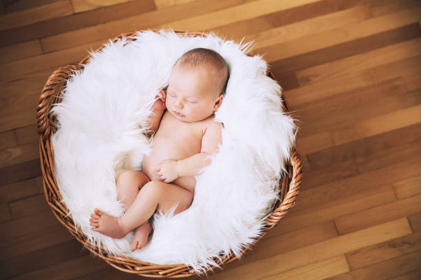 istock Sleeping newborn baby on white blanket in wicker basket. 853843768