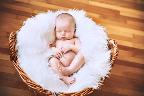 istock Sleeping newborn baby on white blanket in wicker basket. 853843946