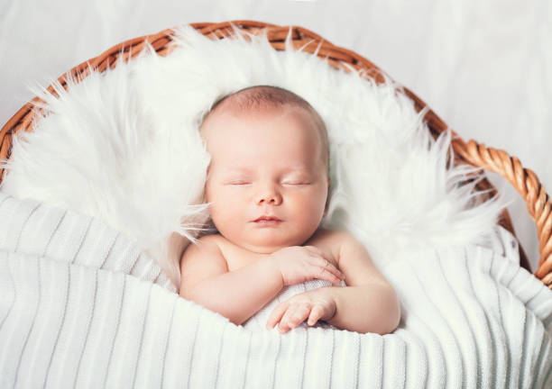istock Sleeping newborn baby on white blanket in wicker basket. 853844154