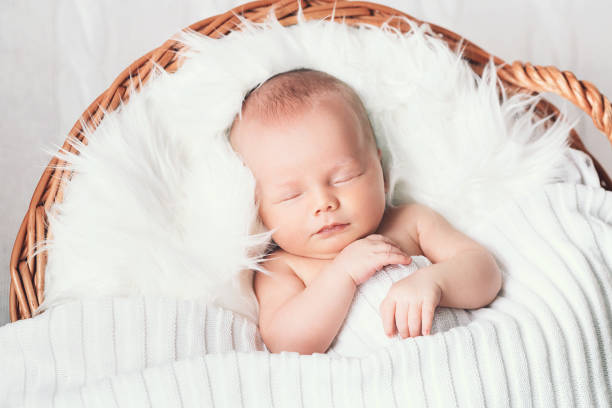 istock Sleeping newborn baby on white blanket in wicker basket. 853844172