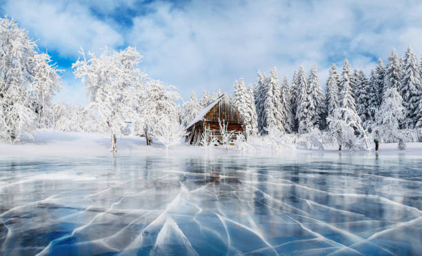 Blue ice and cracks on the surface of the ice. Frozen lake under a blue sky in the winter. Cabin in the mountains. Mysterious fog. Carpathians. Ukraine, Europe Blue ice and cracks on the surface of the ice. Frozen lake under a blue sky in the winter. Cabin in the mountains. Mysterious fog. Carpathians. Ukraine, Europe. hut photos stock pictures, royalty-free photos & images