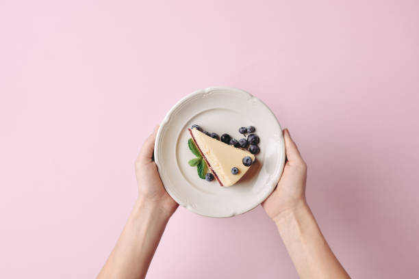 woman holding slice of cheesecake