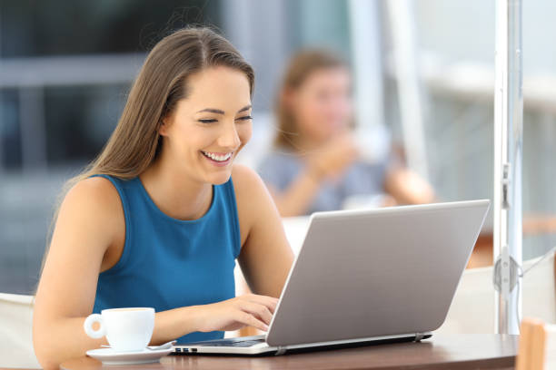 istock Happy woman using a laptop in a bar terrace 853862880