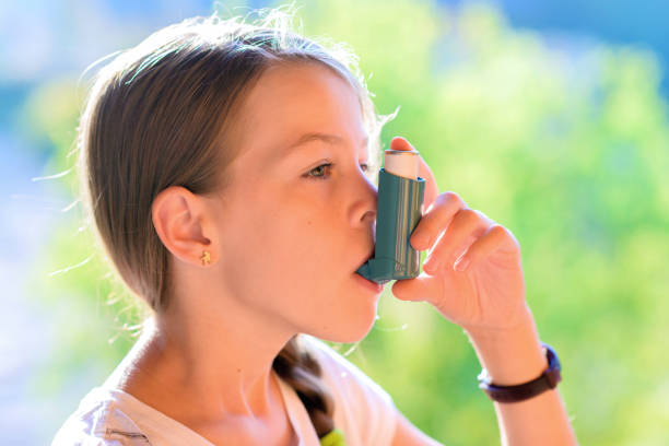 mädchen mit asthma-inhalator in einem park - asthmatic child asthma inhaler inhaling stock-fotos und bilder