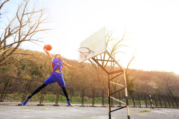 istock Basketball player making slam dunk on court, outdoors 853867414
