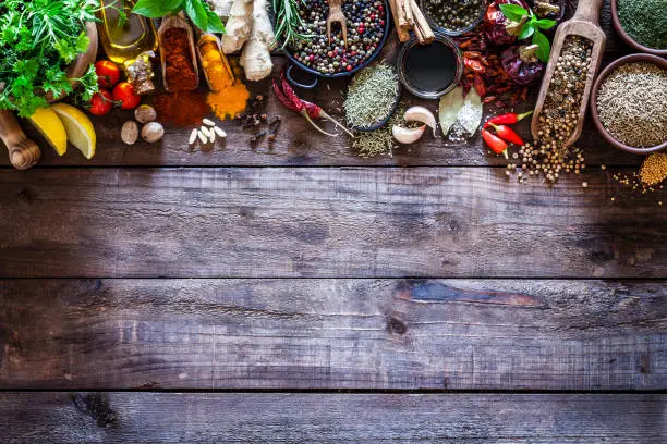 Photo of Spices and herbs border on rustic wood kitchen table