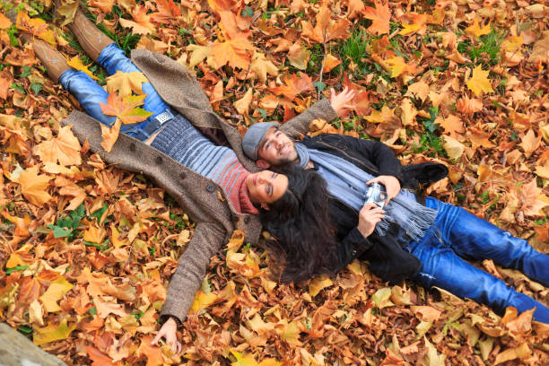 istock Young people lying down on autumn leafs carpet 853878258