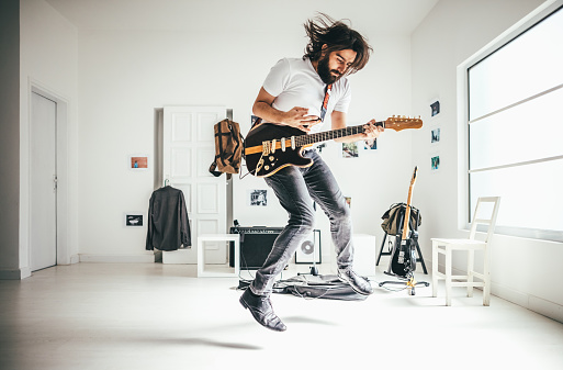 Senior businessman with mouth open singing ecstatically and playing guitar over white background