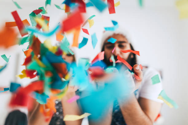 istock Couple blowing confetti out of their hands 853887830