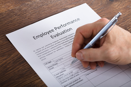 High Angle View Of A Person Filling A Performance Evaluation Form Of Employee