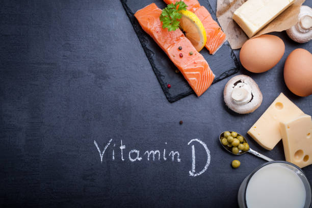 schwarzer schiefer tisch mit produkt reich an vitamin d und omega-3. geschriebene wort vitamin d durch weiße kreide. - vitamin d salmon fillet raw stock-fotos und bilder