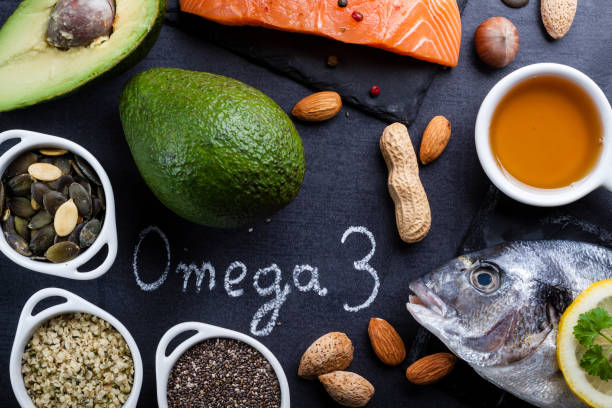 schwarzer schiefer tisch mit produkt reich an omega 3 und vitamin d. wort omega 3 von weiße kreide geschrieben. - vitamin d salmon fillet raw stock-fotos und bilder