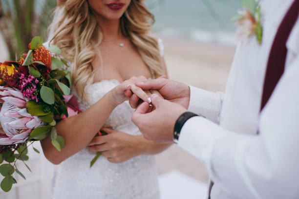 istock Groom hand putting a wedding ring on the bride finger 853904504