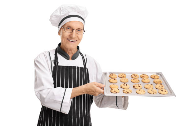istock Elderly baker holding a tray with freshly baked cookies 853907166