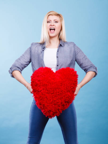 istock Happy woman holding red pillow in heart shape 853908628