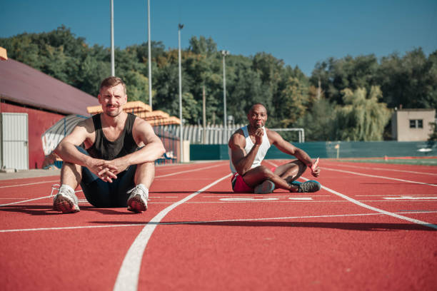 istock A white athlete and a black man with a lollipop sit at the stadium 853909052