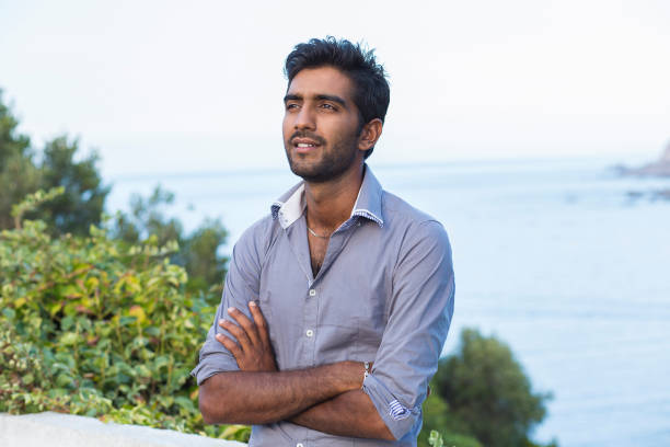 istock Young Indian business Man thinking isolated outdoors green trees blue sea Background 853915708